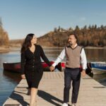 Couple walking on a boardwalk along North Saskatchewan River holding hands and looking at each other