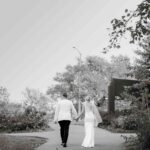 A bride and groom walking while holding hands outside a wedding venue called Bison Lodge in Edmonton, Alberta