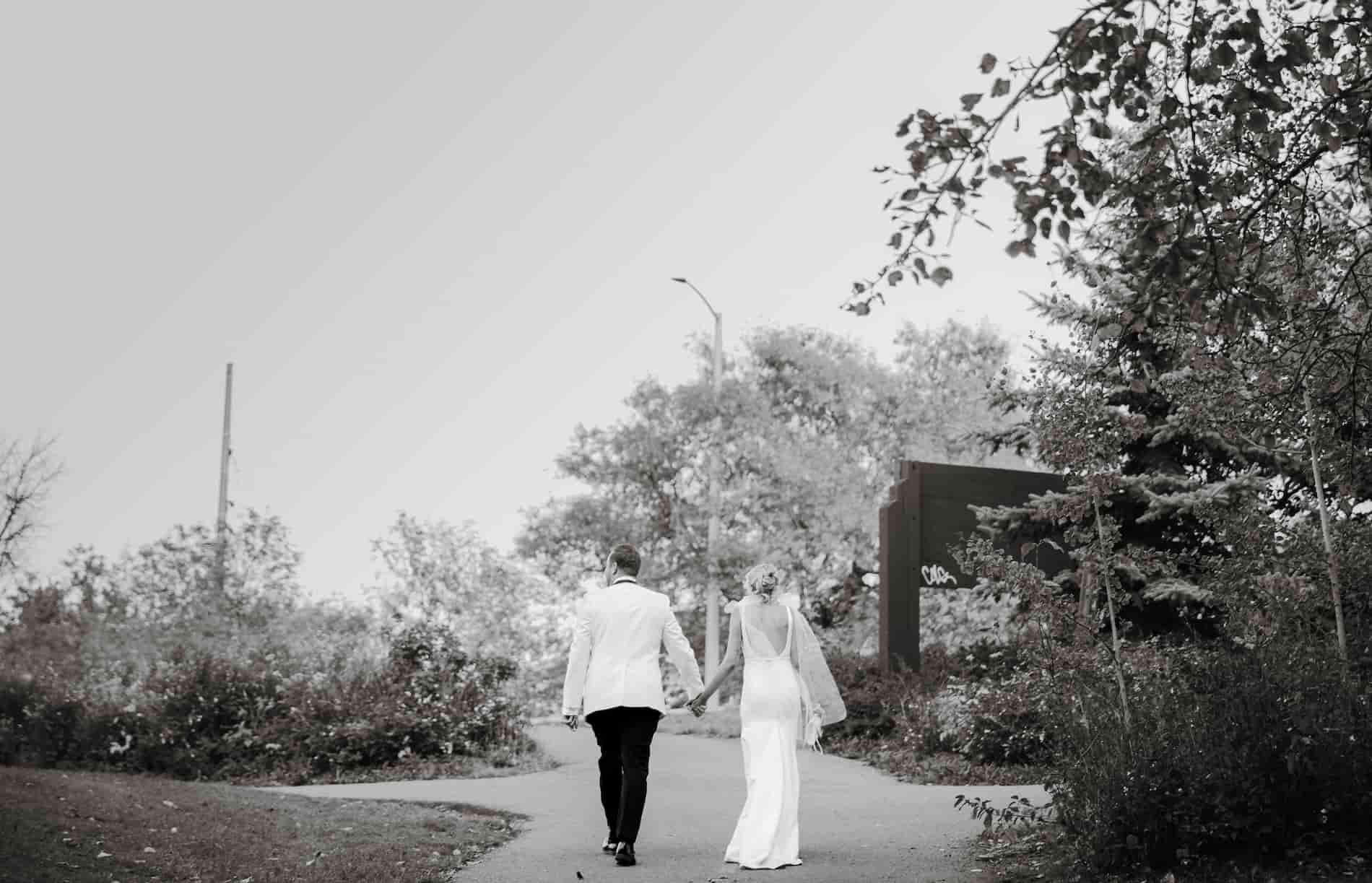 A bride and groom walking while holding hands outside a wedding venue called Bison Lodge in Edmonton, Alberta