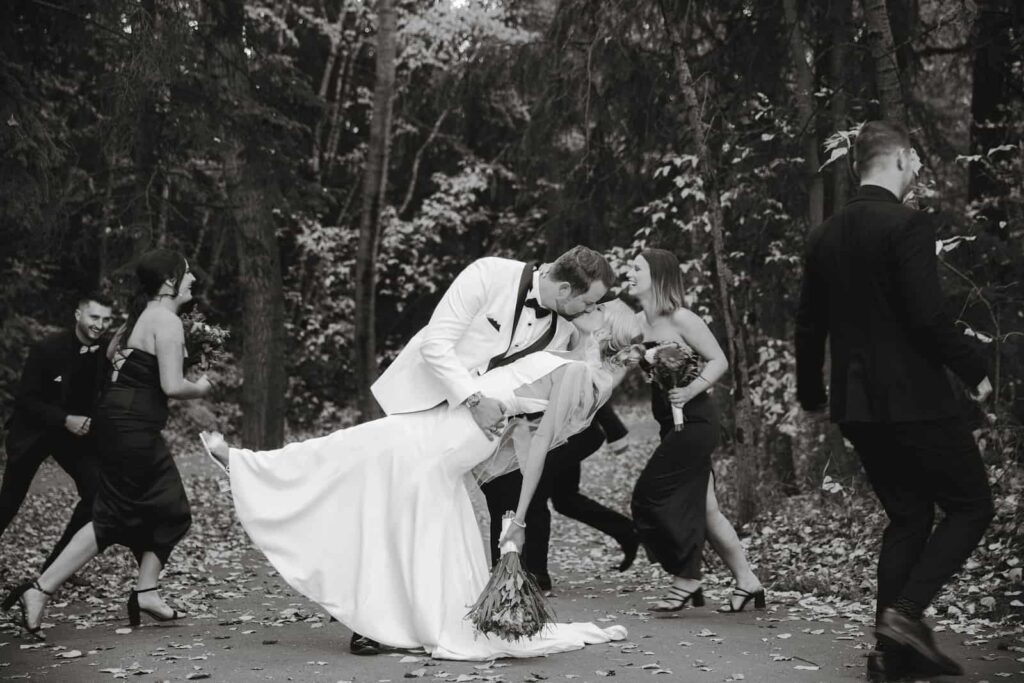 Bride and groom kissing in the woods with their bridal party