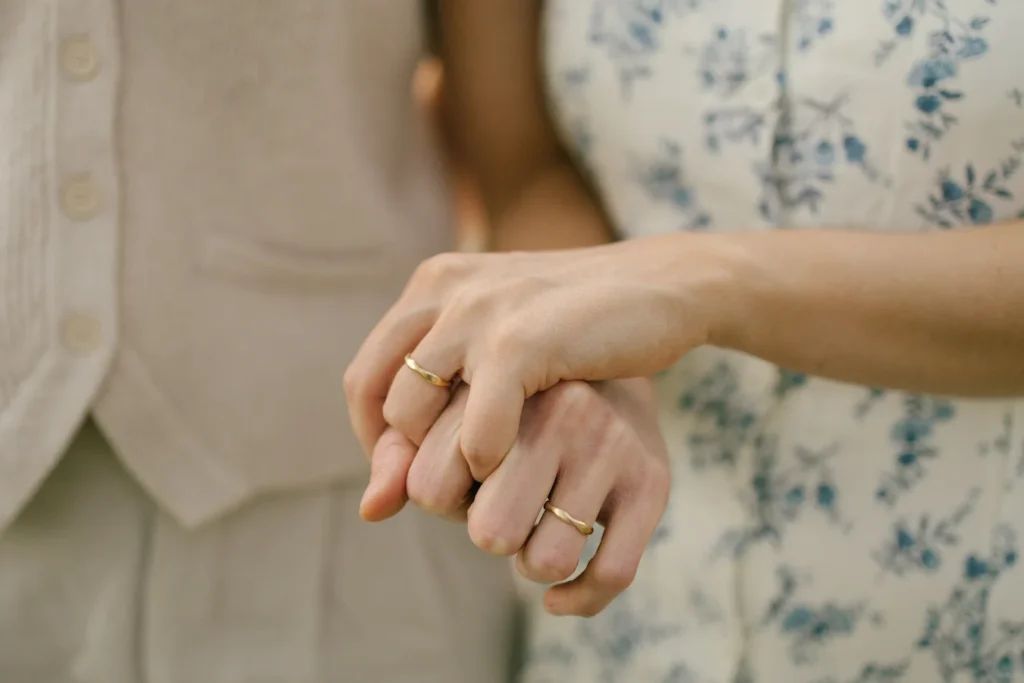 two hands clasped together with gold wedding bands