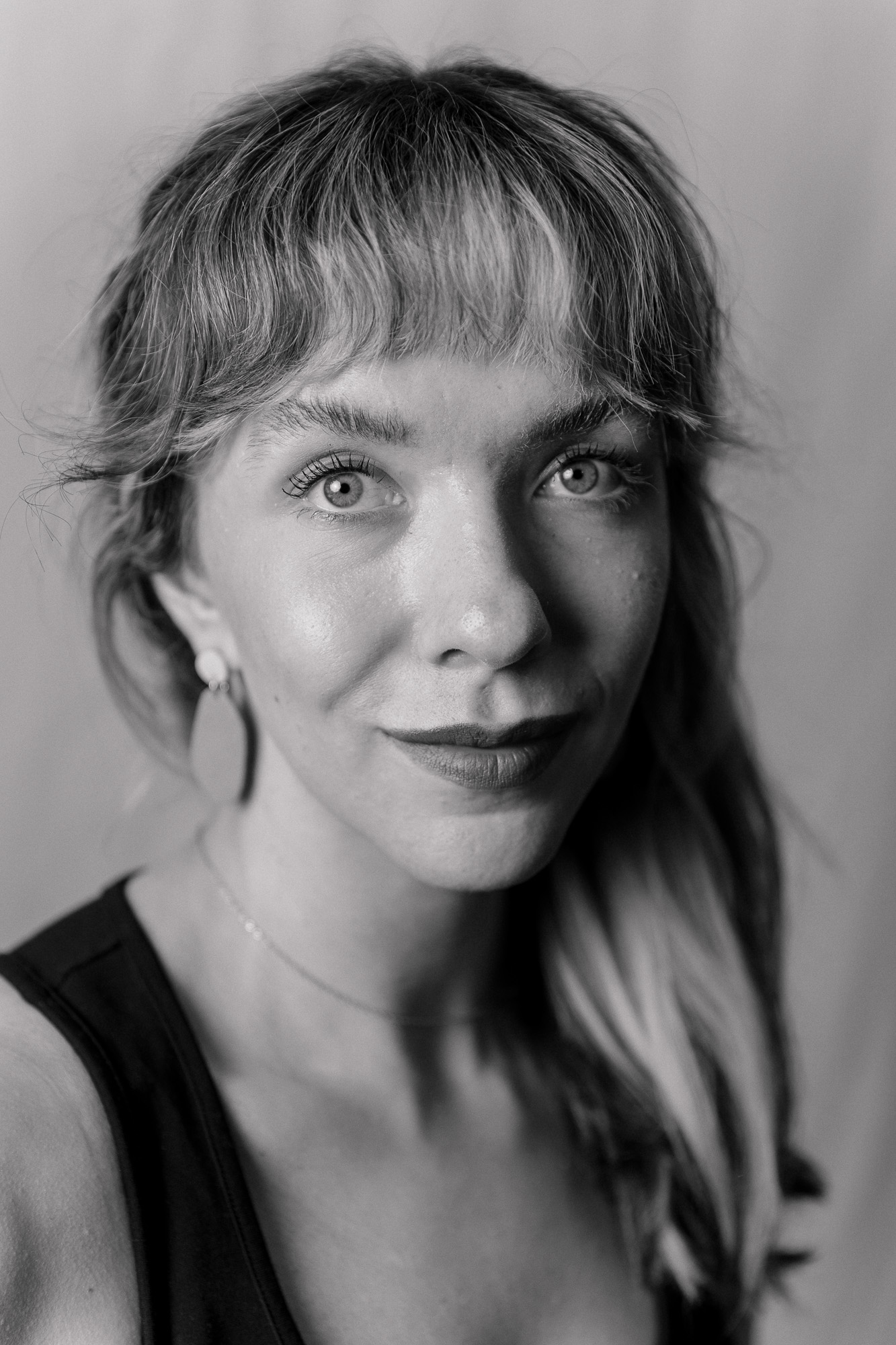 black and white portrait of a woman with bangs looking at the camera and with her hair down over her left shoulder