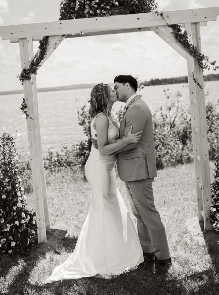 Bride and groom sharing a kiss during an outdoor wedding ceremony near Bonnyville, Alberta