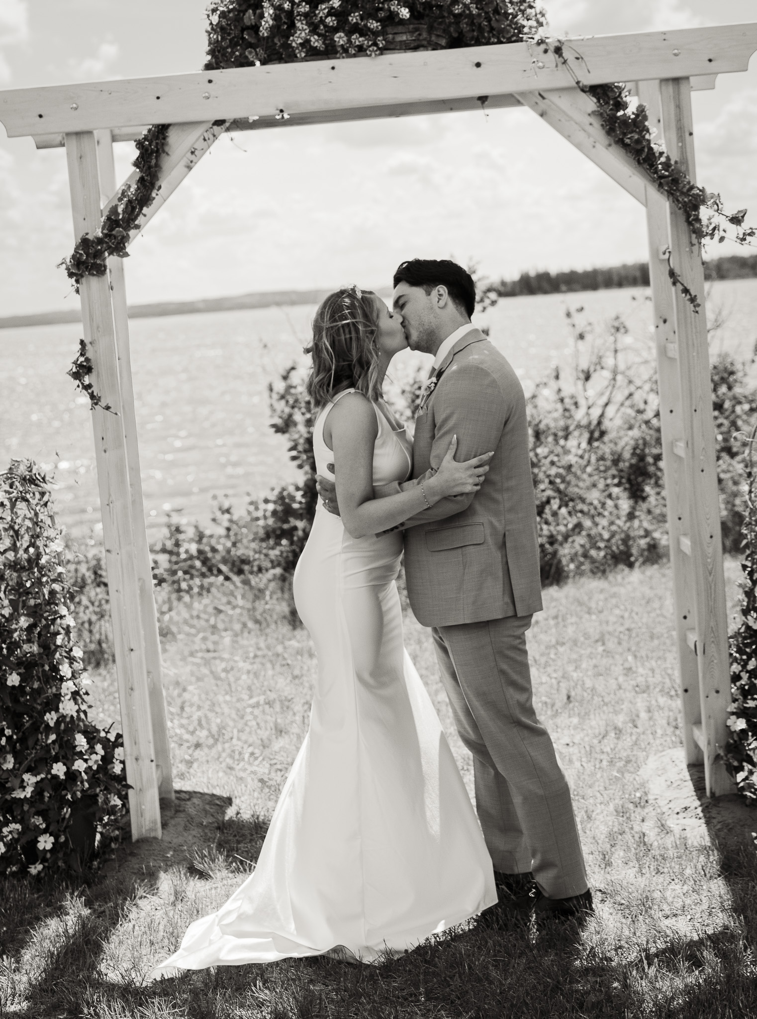 Bride and groom sharing a kiss during an outdoor wedding ceremony near Bonnyville, Alberta