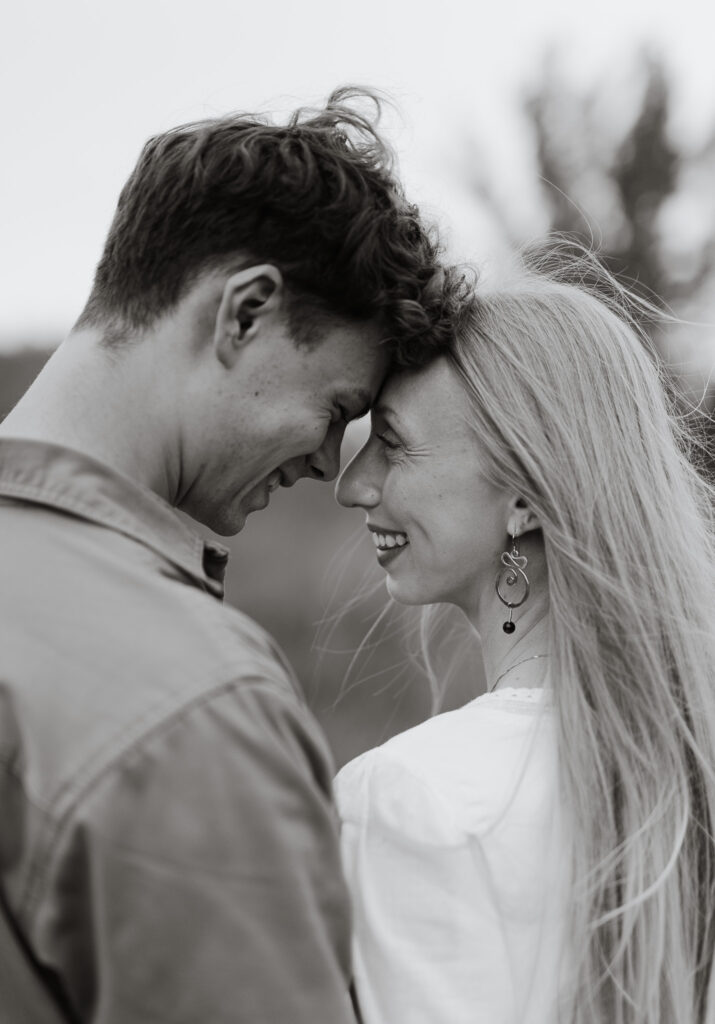 Black and white close-up portrait of an engaged couple smiling with their foreheads touching during an engagement session at Terwillegar Dog Park in Edmonton, Alberta.