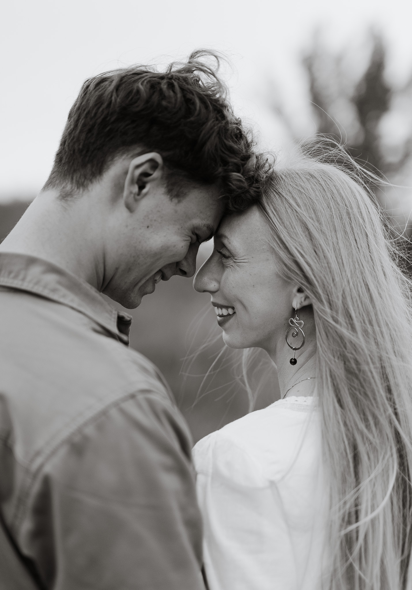 Black and white close-up portrait of an engaged couple smiling with their foreheads touching during an engagement session at Terwillegar Dog Park in Edmonton, Alberta.