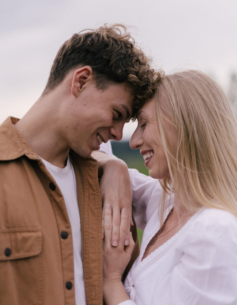 Close-up portrait of an engaged couple smiling forehead to forehead during an engagement session at Terwillegar Dog Park in Edmonton, Alberta.