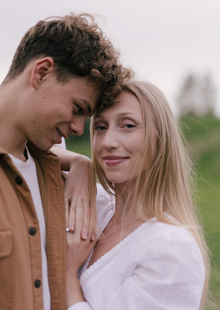 Close-up portrait of an engaged couple at Terwillegar Dog Park in Edmonton, with the engagement ring visible on the bride-to-be's hand.