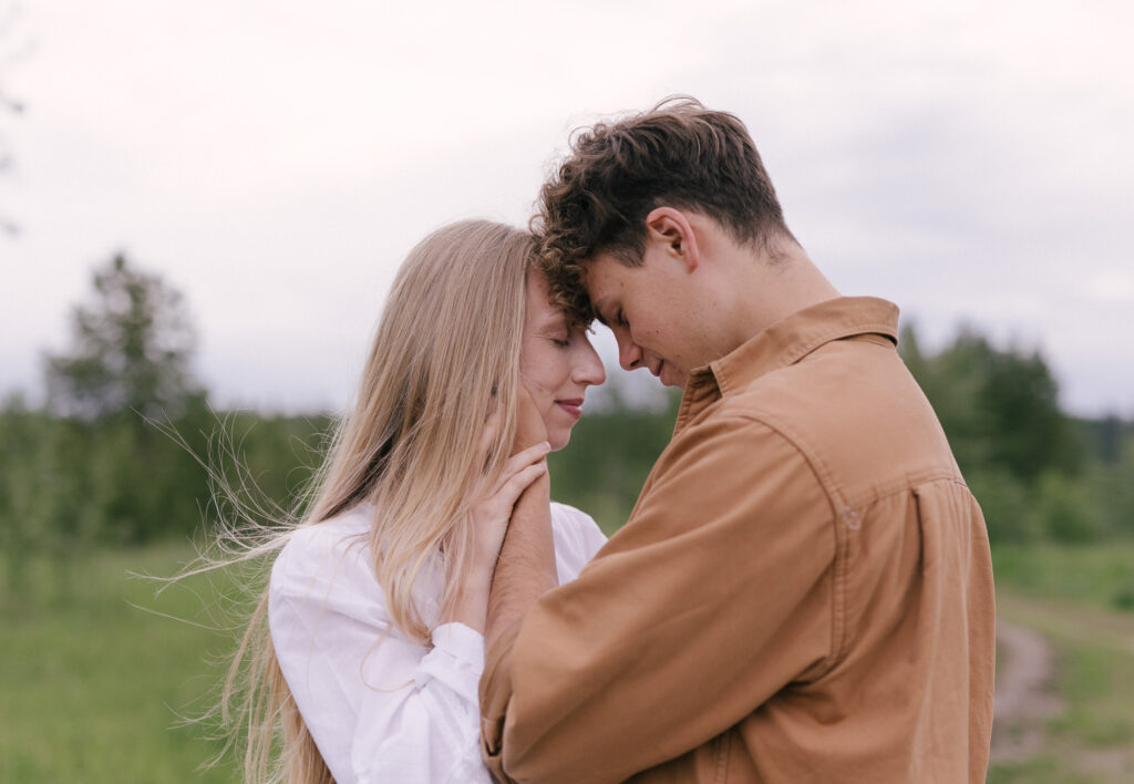 Engaged couple embracing with their foreheads touching during an engagement session at Terwillegar Dog Park in Edmonton, Alberta.