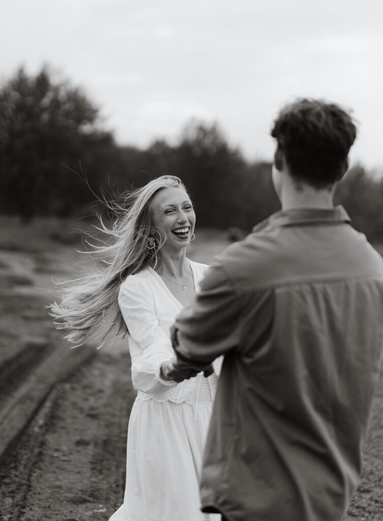 Black and white photo of an engaged couple laughing together during an engagement session at Terwillegar Dog Park in Edmonton, Alberta.