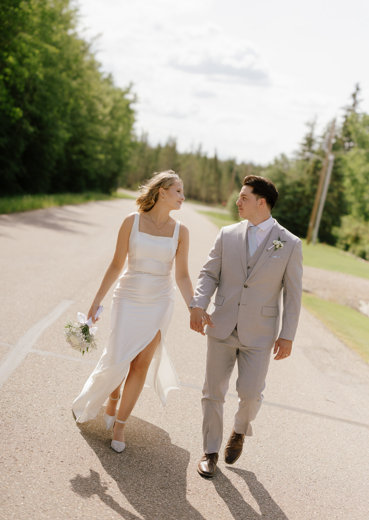 Bride and groom walking together on a rural road in Bonnyville, Alberta