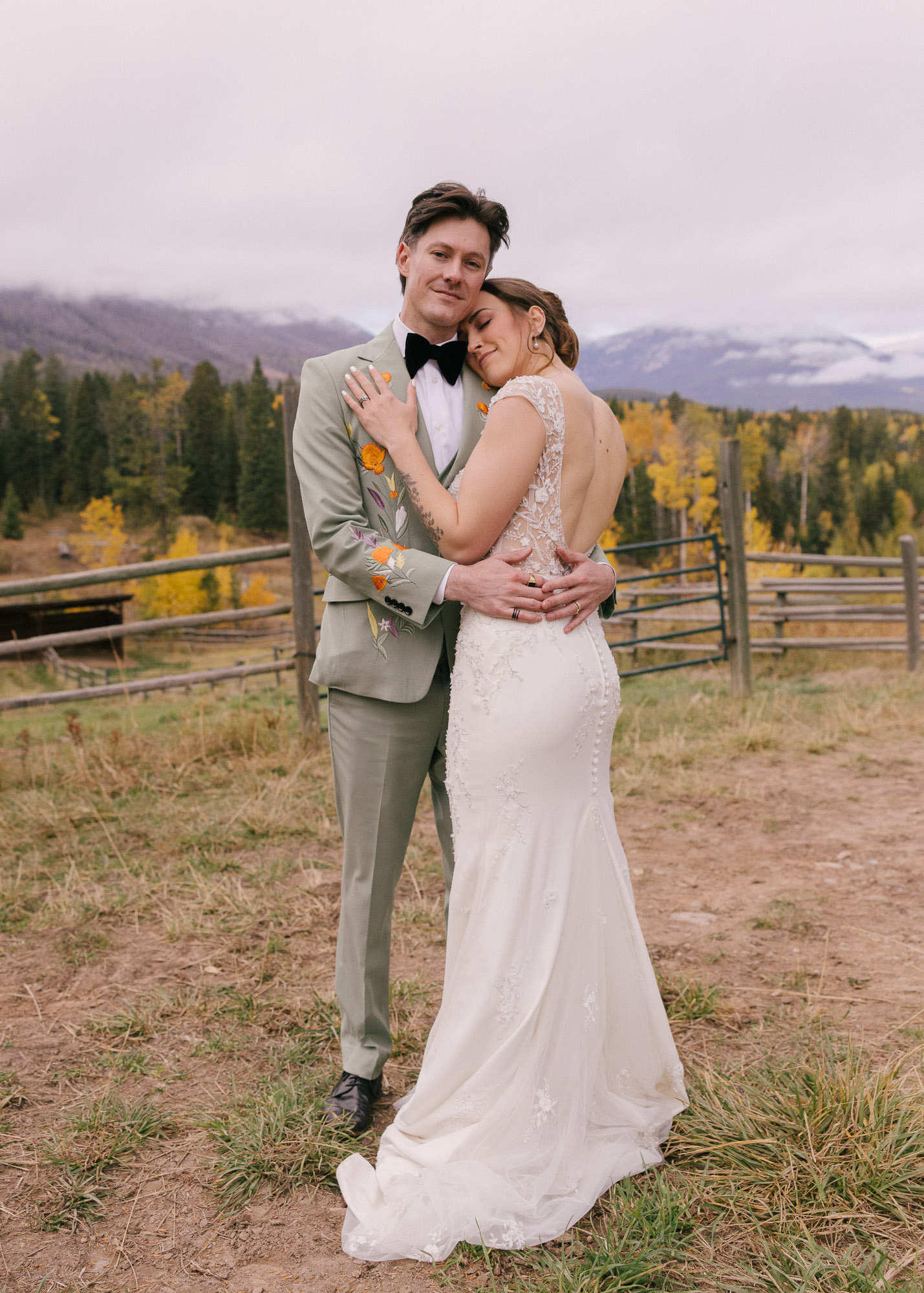 Bride and groom sharing a romantic moment during their fall wedding in Invermere, British Columbia, surrounded by autumn trees.